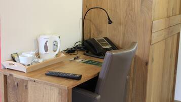 A wooden desk with a coffee maker, a phone, and a remote control.