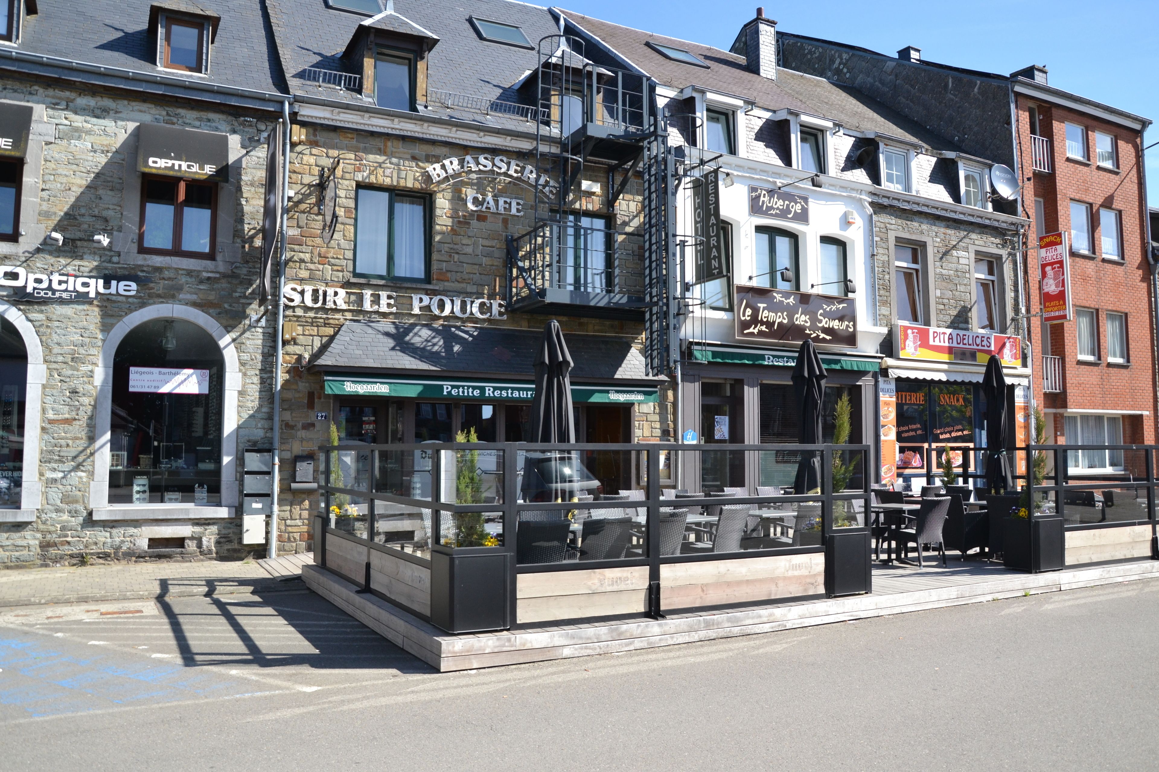 A street view of a row of cafes and restaurants with outdoor seating.