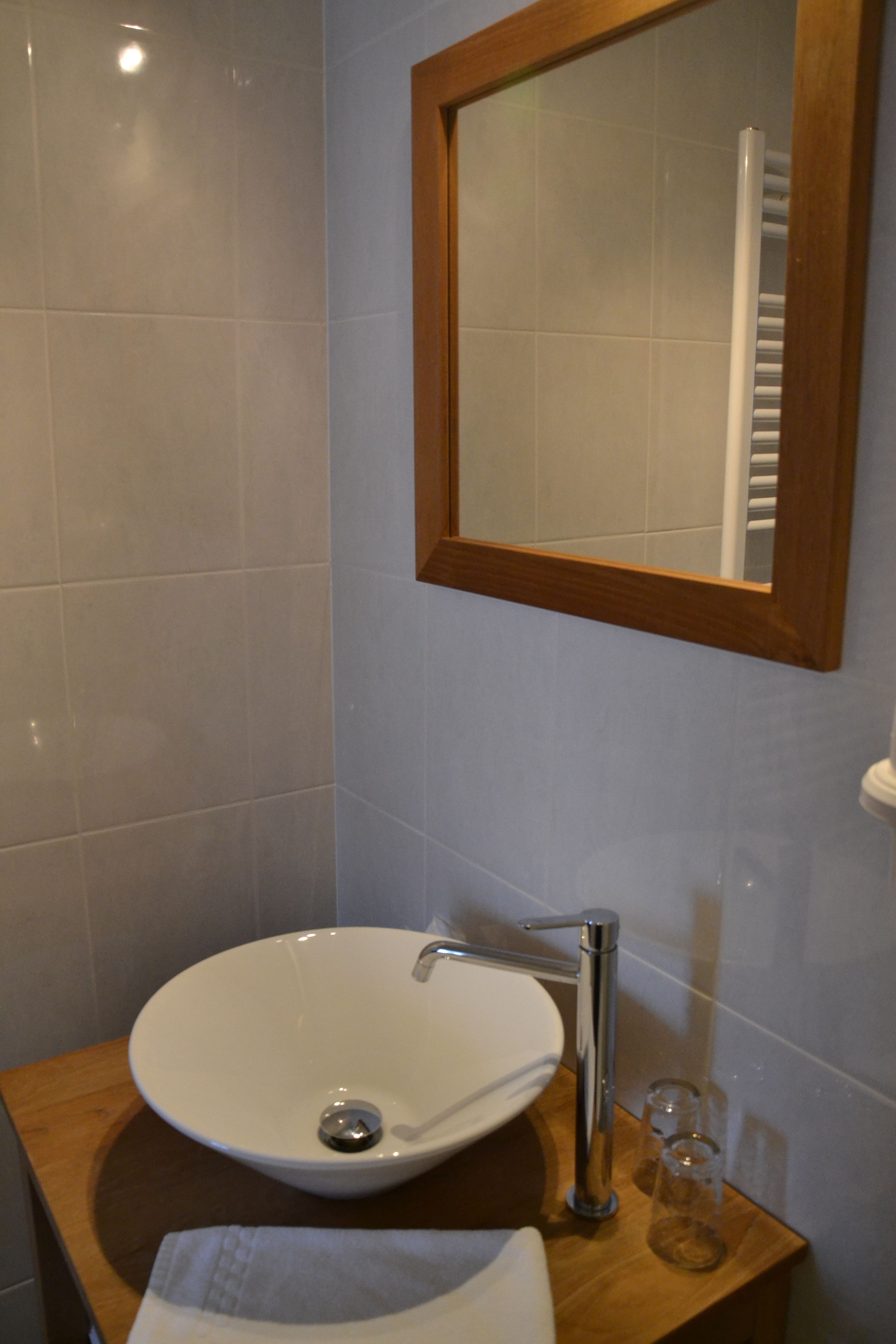 Ein Badezimmer mit Waschbecken, Holzschrank, Spiegel und Handtuch.