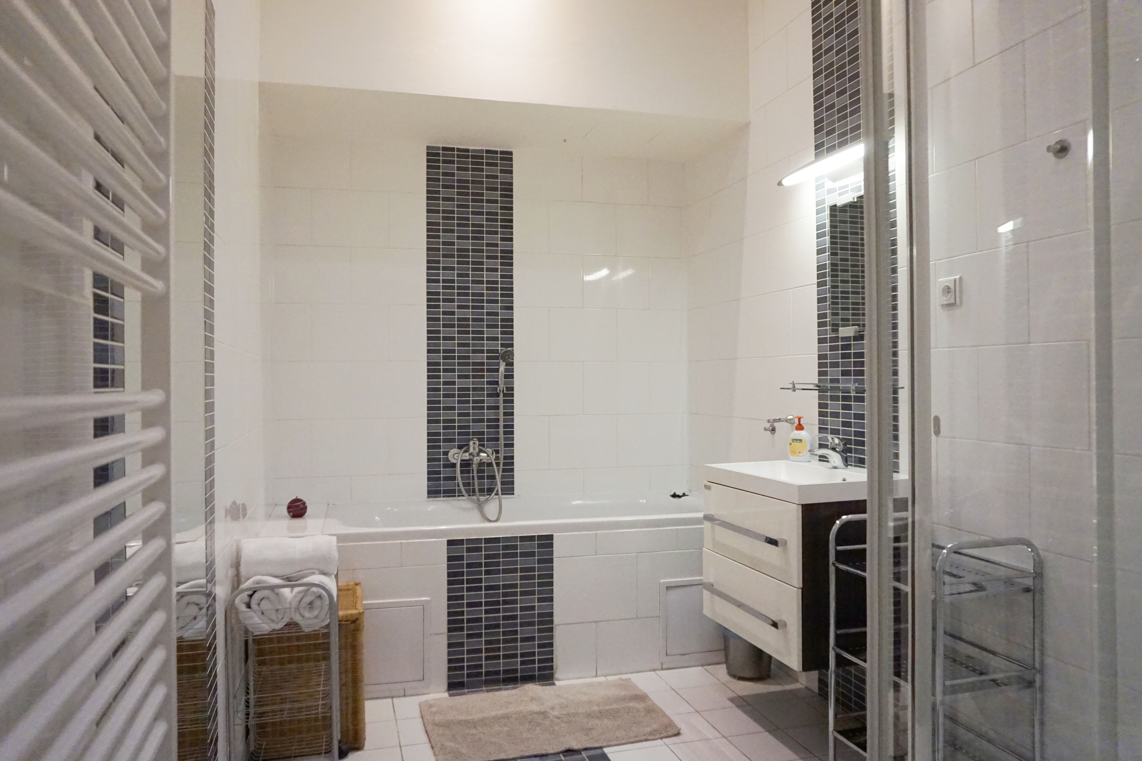 A modern bathroom with a bathtub, a shower, and a vanity with a mirror.