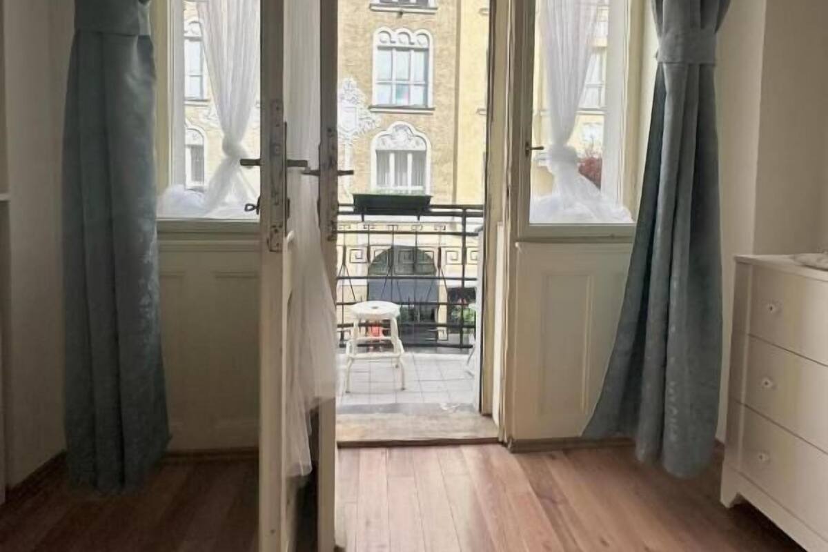 An open door leading to a balcony with a view of a building.