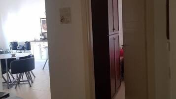 A hallway leading to a kitchen area with a refrigerator and a dining table with chairs.