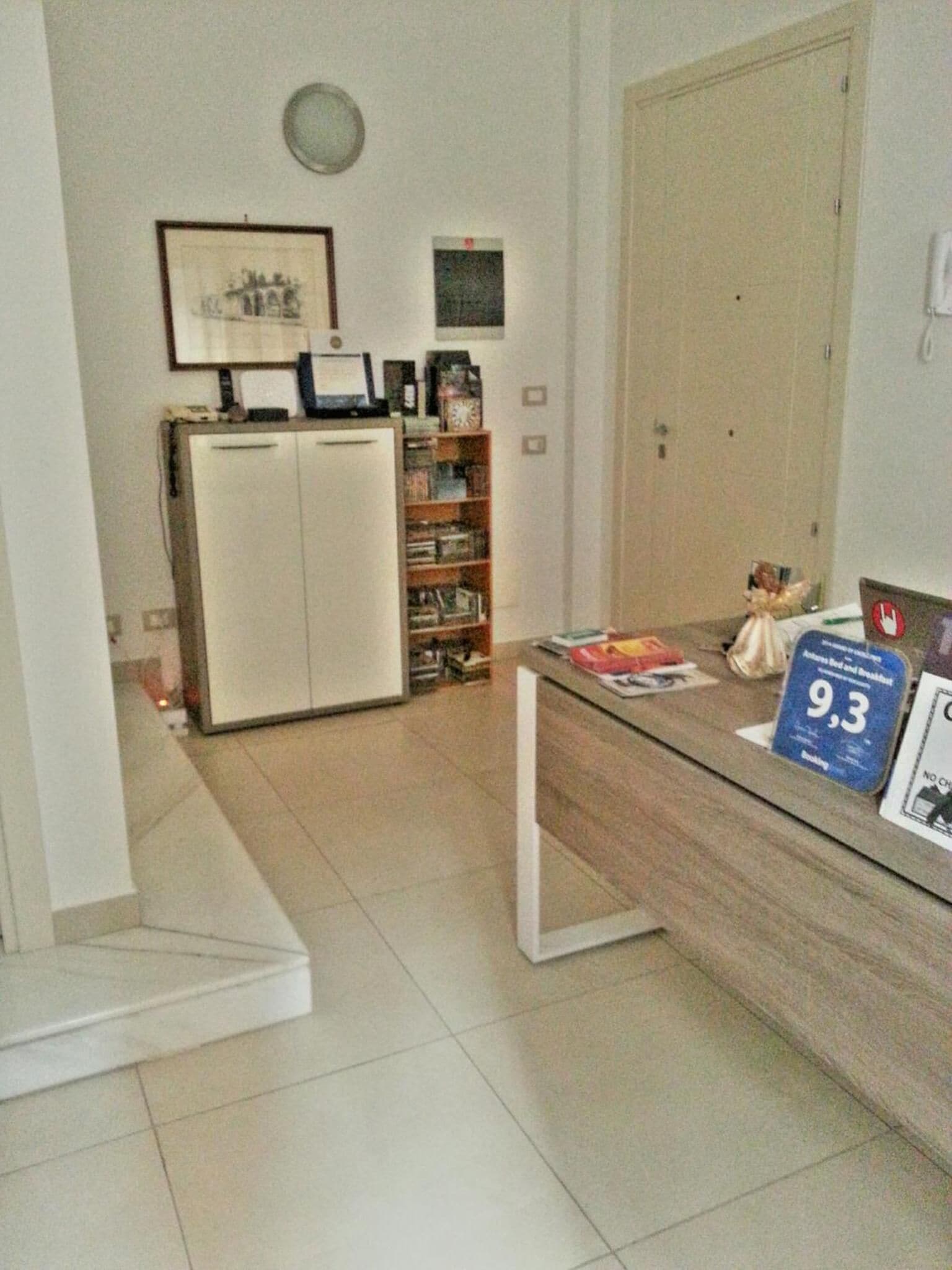 A room with a desk, a bookshelf, a door, and a clock on the wall.