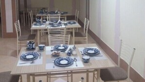 A dining area with multiple tables set for meals, chairs, and a decorative wall piece. - Hotel Abu Shakheen (Bukhara)
