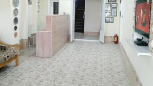 A living room with a patterned sofa, a wooden reception desk, and a tiled floor. - Hotel Abu Shakheen (Bukhara)