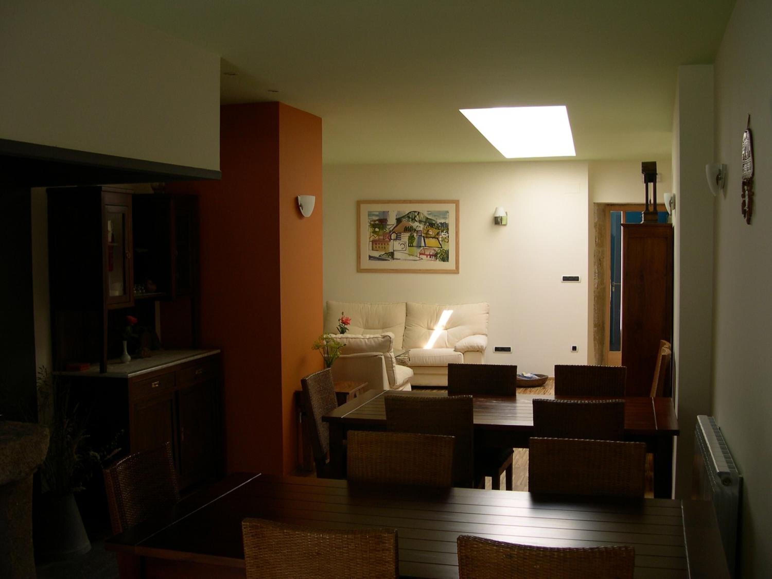 A living room with a sofa, dining table, chairs, and a painting on the wall.