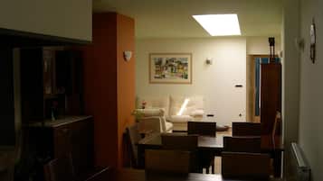 A living room with a sofa, dining table, chairs, and a painting on the wall.
