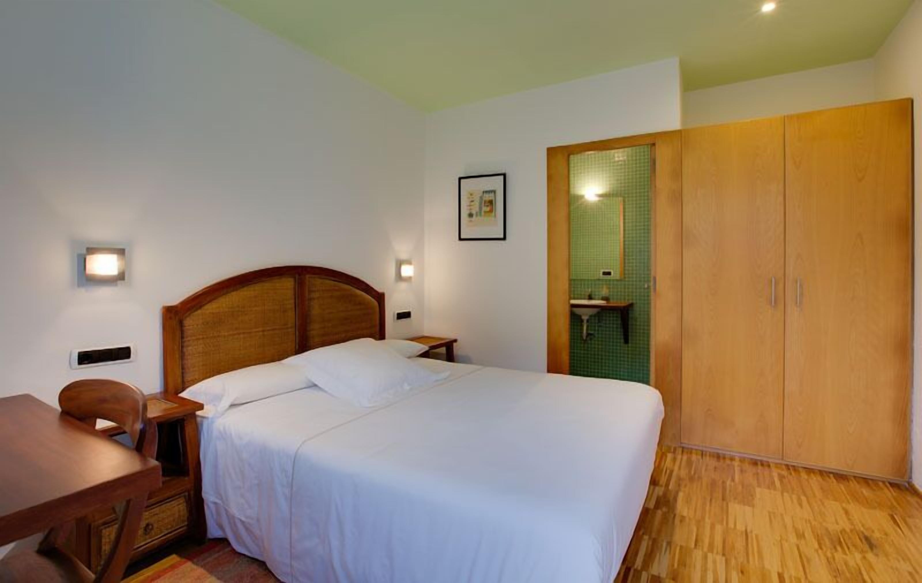 Ein Schlafzimmer mit einem hölzernen Bett, Nachttischen, einem Schreibtisch und einem Kleiderschrank.