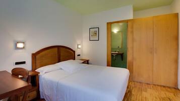 Ein Schlafzimmer mit einem hölzernen Bett, Nachttischen, einem Schreibtisch und einem Kleiderschrank.