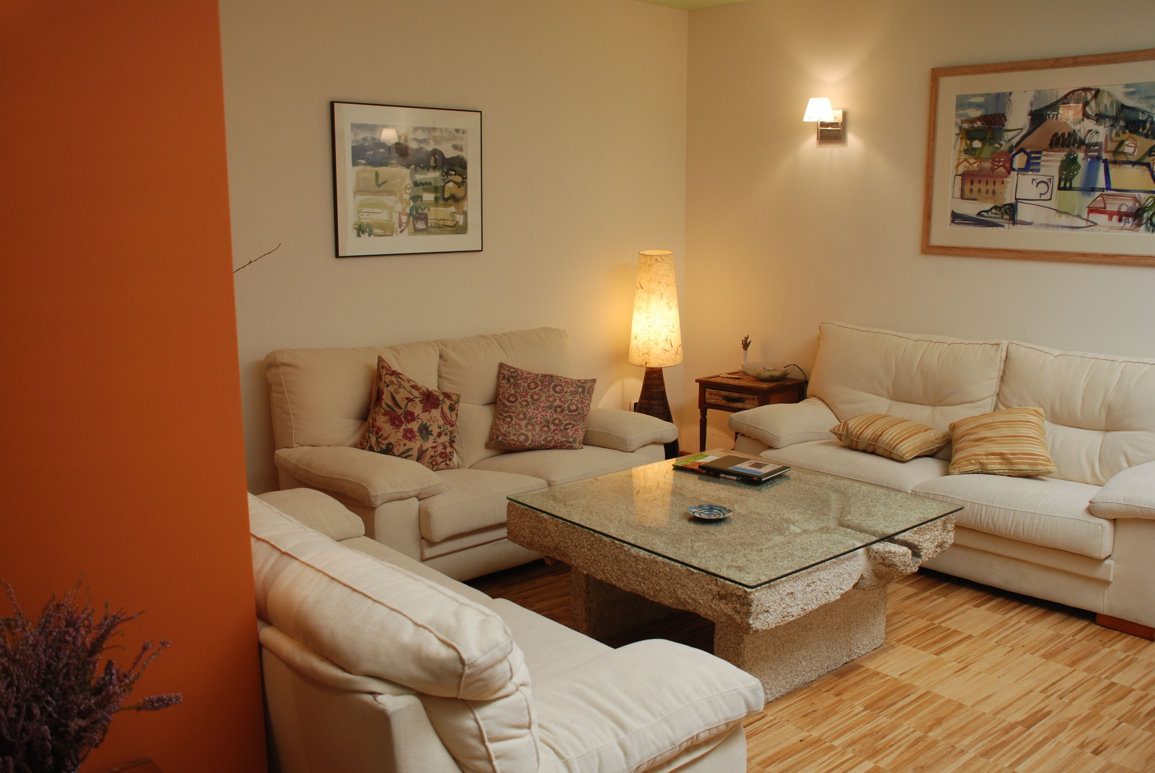 A living room with a glass coffee table, two sofas, a lamp, and framed artwork on the walls.