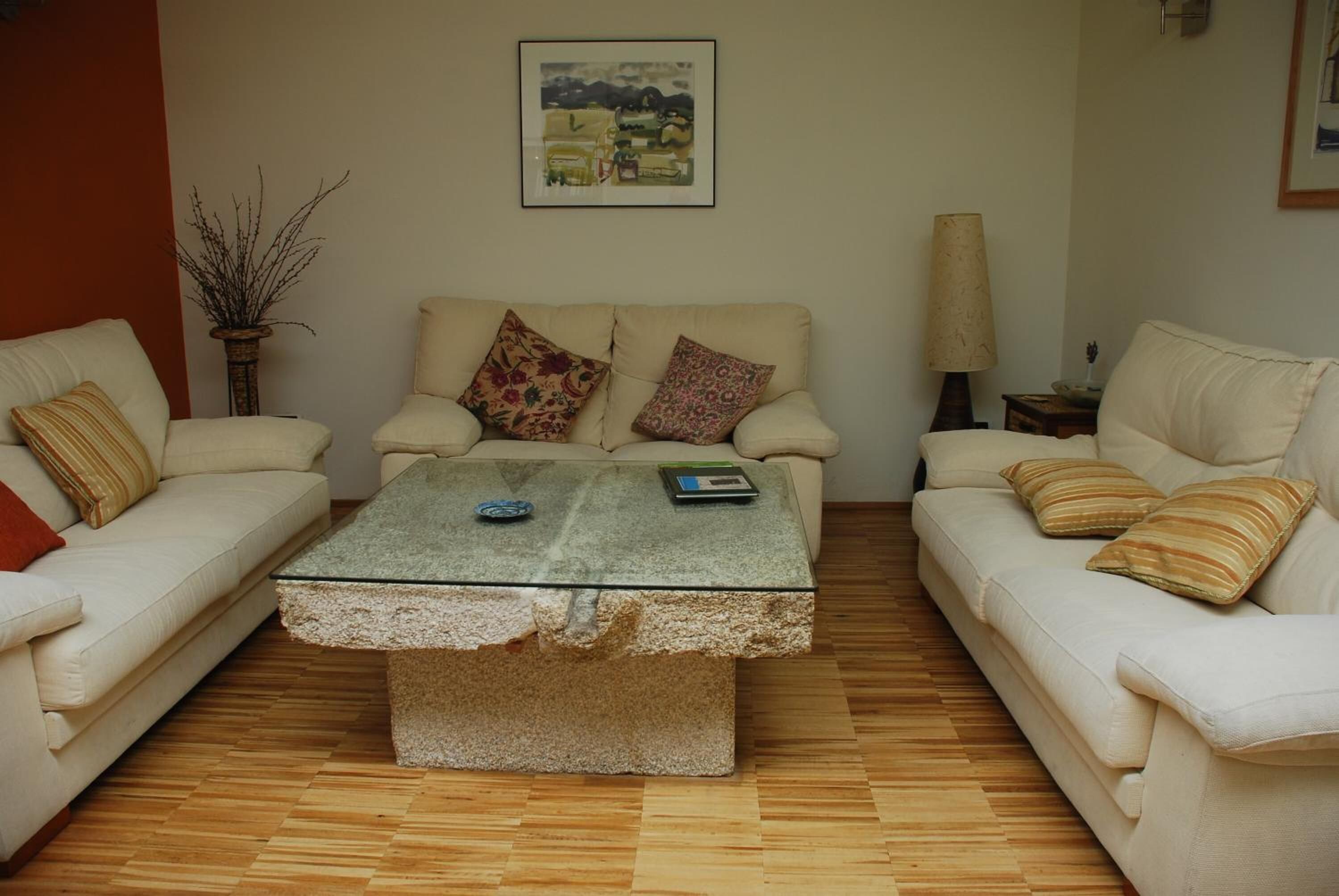 A living room with two white sofas, a glass coffee table, and a lamp on a side table.