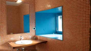 Un baño con pared de azulejos, un lavabo con espejo y una pared azul decorativa.
