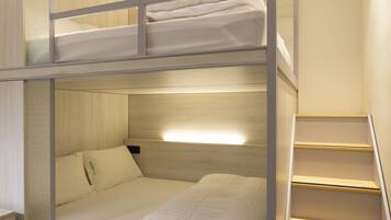 A bunk bed room with a wooden floor, a staircase, and a wall-mounted shelf.