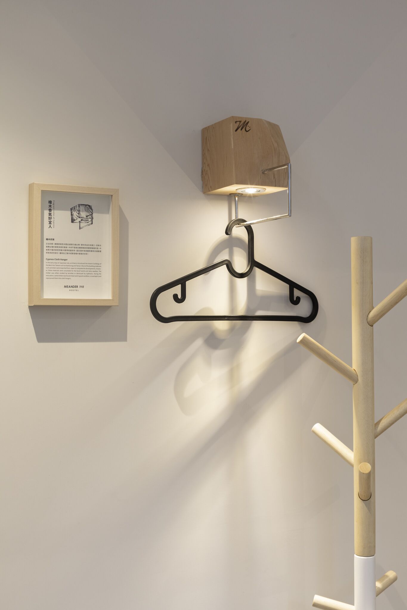 A wall-mounted coat rack with a hanging coat and a framed informational plaque.