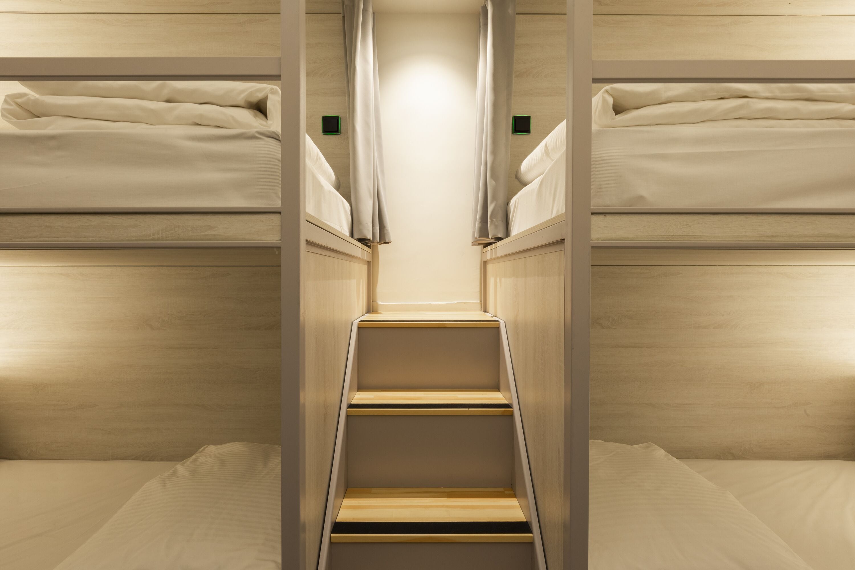 A narrow, wooden bunk bed room with a central staircase.