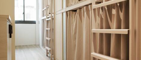 A room with a wooden floor, a window with curtains, and a white door.