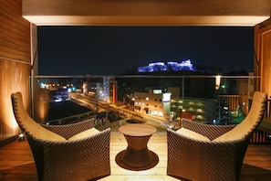 A balcony with wicker chairs and a table, overlooking a cityscape at night. - The Shiroyama Terrace Tsuyama Villa (Tsuyama)