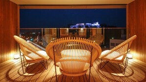 Een balkon met rieten stoelen en uitzicht op een stadsbeeld bij nacht.