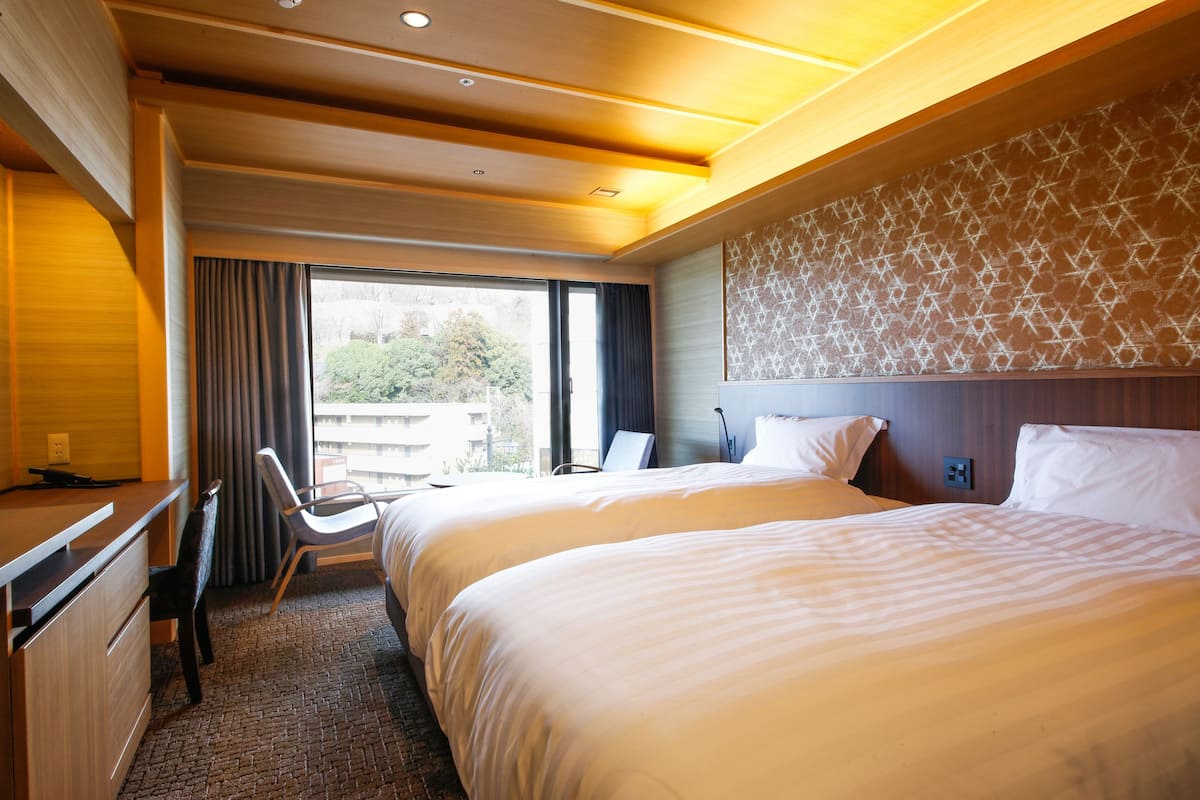 Une chambre d’hôtel avec deux lits, un bureau et une chaise.