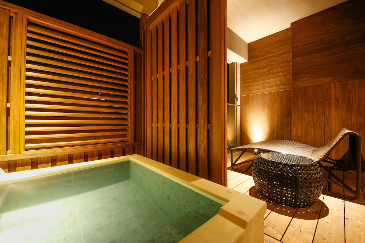Un espace de détente en bois comprenant un bain à remous et un fauteuil.