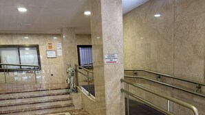 Vestíbulo con suelo de mármol, una estatua, una puerta cerrada y un letrero que indica que está cerrada.
