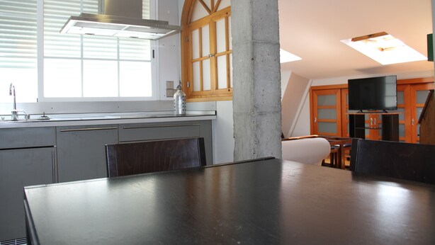 Una cocina moderna con un ventanal grande, estufa integrada y un comedor con mesa y sillas.