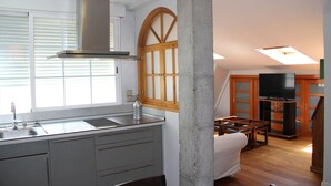 Una cocina moderna con estufa integrada, un ventanal amplio y un comedor con mesa y sillas de madera.