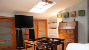 Una habitación con tragaluz, muebles de madera, televisión y un armario.