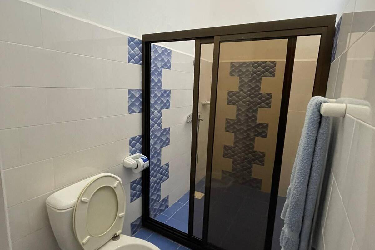A bathroom with a toilet, a shower with a glass door, and blue-tiled walls.