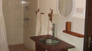 Une salle de bain avec un lavabo en verre, une douche et un miroir.