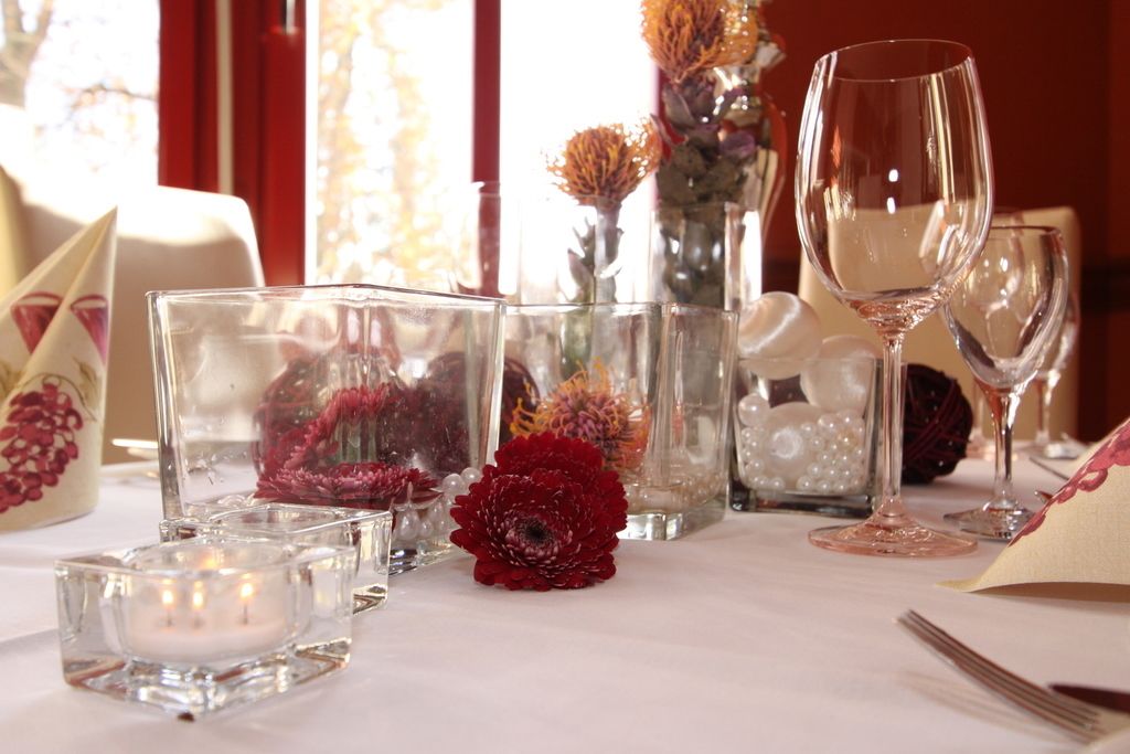 A table set with clear glassware, candles, and decorative flowers.