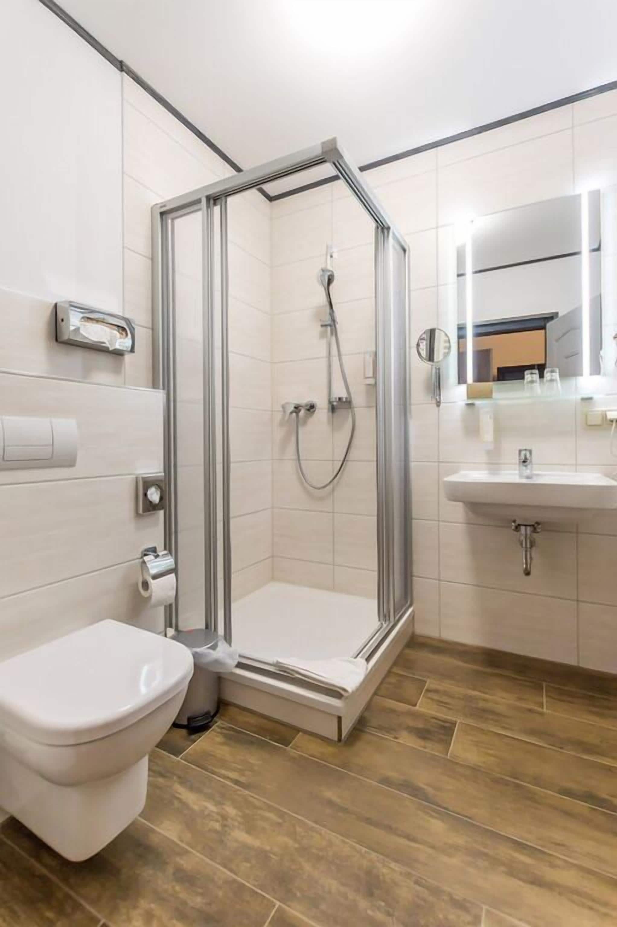 Un baño moderno con ducha de mampara de vidrio, inodoro y lavabo.