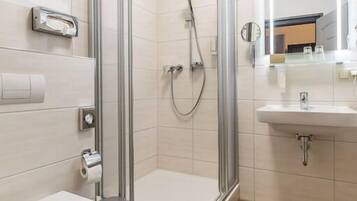 Un baño moderno con ducha de mampara de vidrio, inodoro y lavabo.