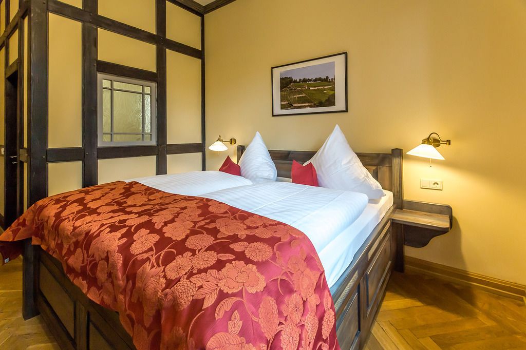 Un dormitorio con una cama grande, dos lámparas de noche, un cuadro enmarcado en la pared y una ventana con vistas al paisaje.