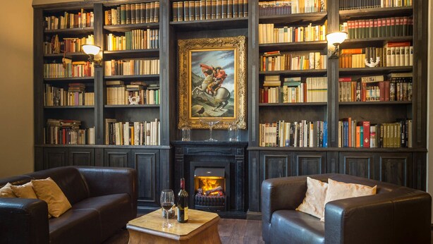 A library with leather sofas, a fireplace, and bookshelves filled with books. - Waldschlösschen Wangen (Nebra)