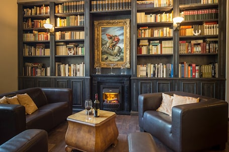 A library with leather sofas, a fireplace, and bookshelves filled with books.