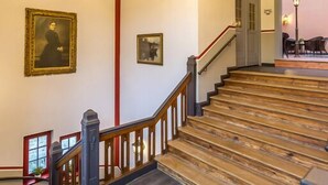 A grand staircase with wooden steps and a metal railing, leading to an upper floor. - Waldschlösschen Wangen (Nebra)