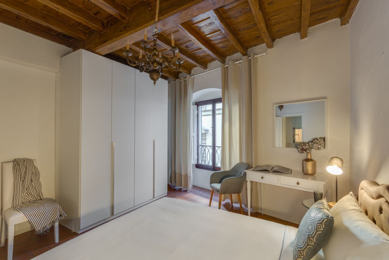 A bedroom with a wooden ceiling, a bed, a desk, a chair, and a wardrobe.