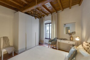 Un dormitorio con techo de madera, cama, escritorio, silla y armario.