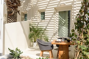 Une terrasse avec une table et une chaise en bois, une plante en pot et un palmier.