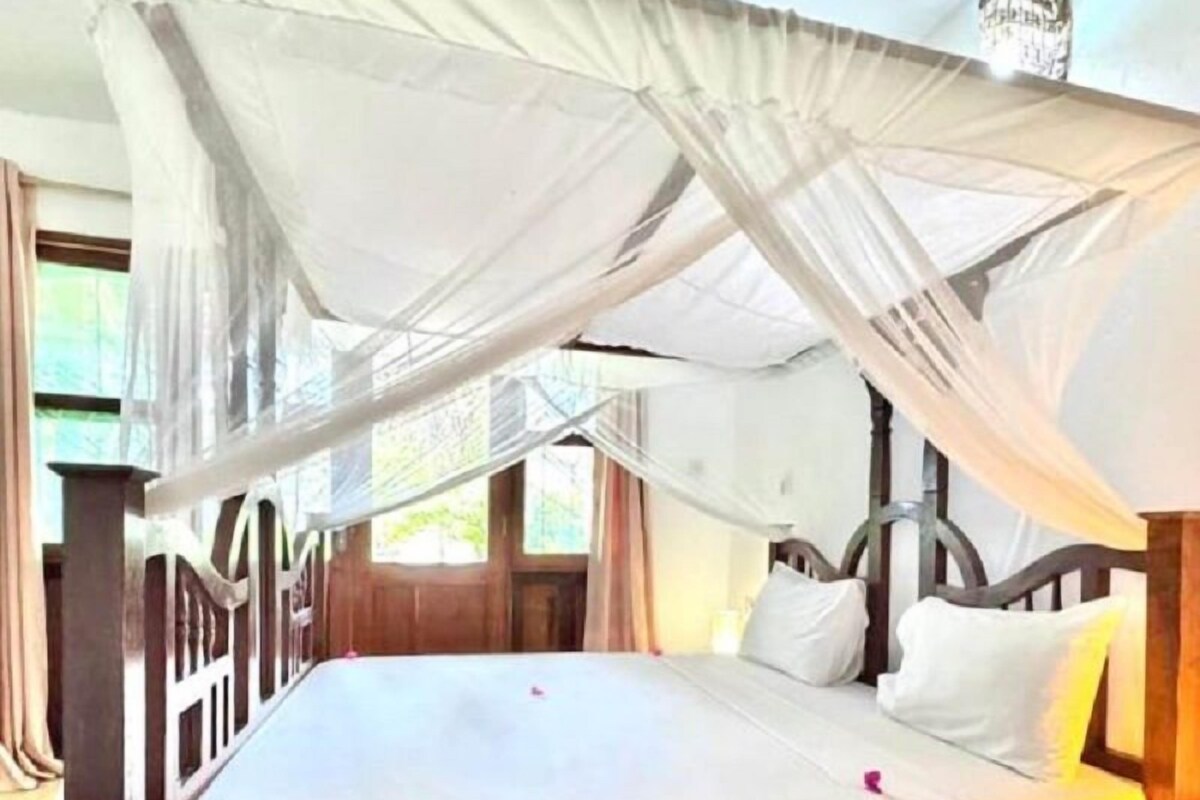 A bed with a canopy, wooden headboard, and white bedding.