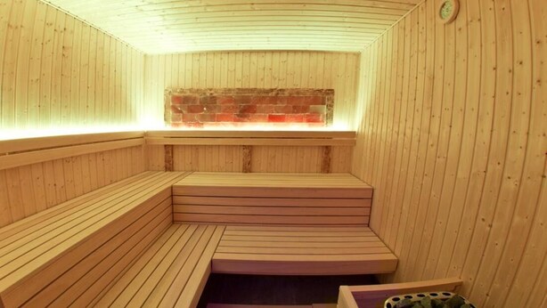 Una sauna con bancos de madera y pared de ladrillo.
