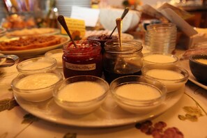 A table with various food items including jars of jam and bowls of creamy dessert. - Agriturismo Melo in Fiore (Maser)
