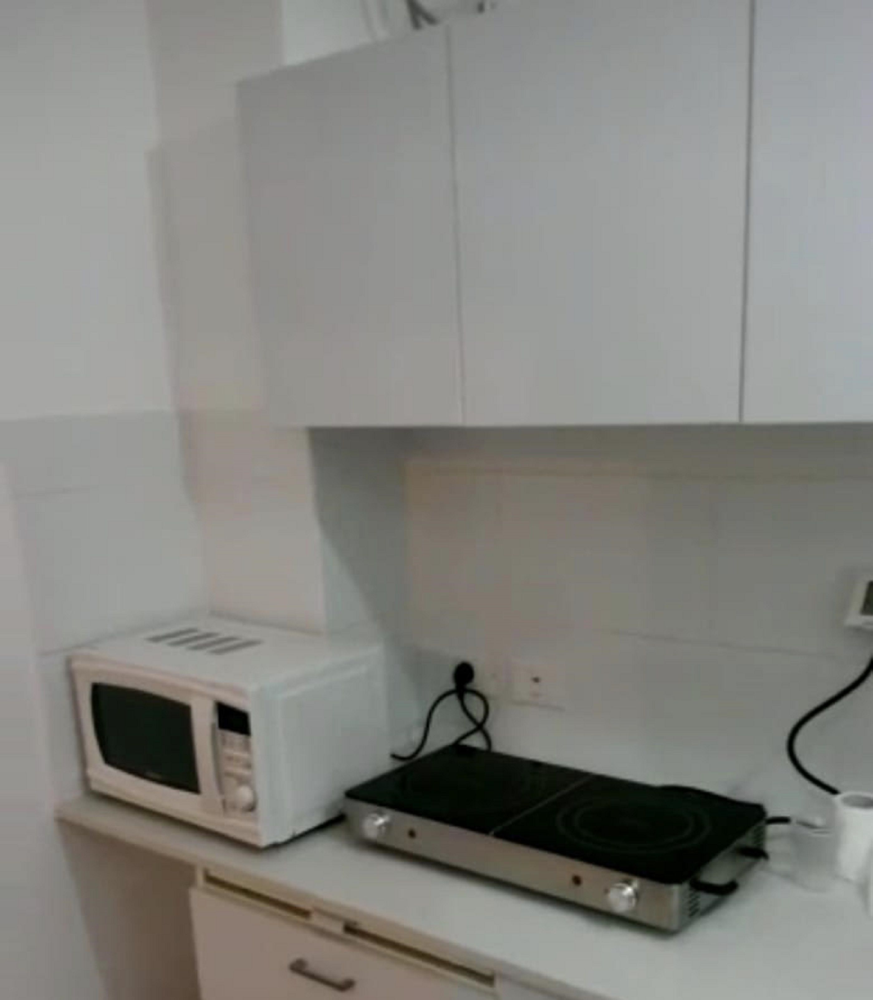 A kitchen with white cabinets, a microwave, a stove, and a roll of paper towels.