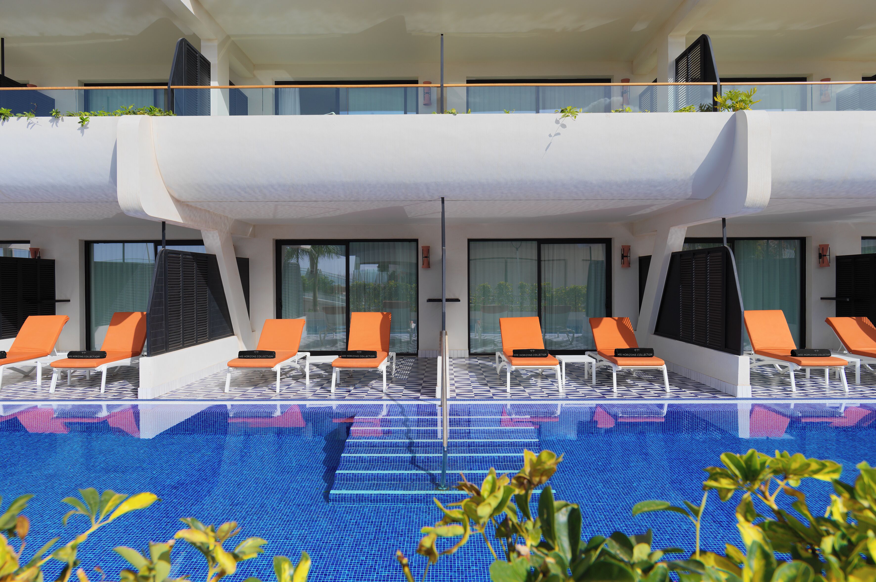 A poolside area with lounge chairs and a clear blue pool.