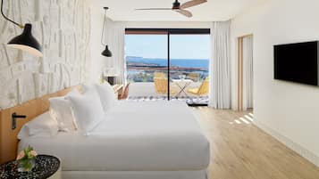 Ein modernes Hotelzimmer mit einem großen Bett, einem Deckenventilator, einem Fernseher und einem Balkon mit Meerblick.