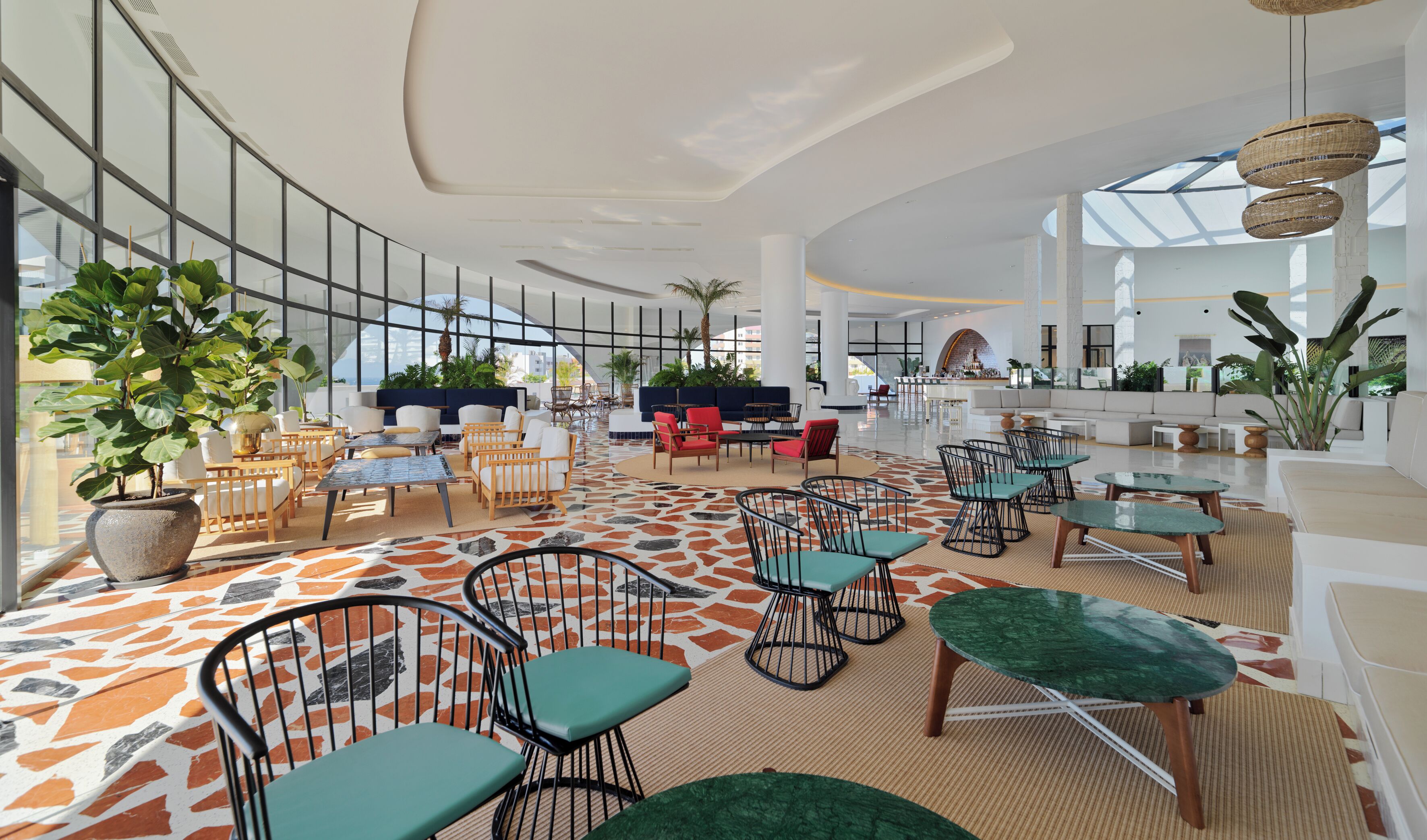 Een ruime binnenruimte met zitplaatsen, grote ramen en kamerplanten.