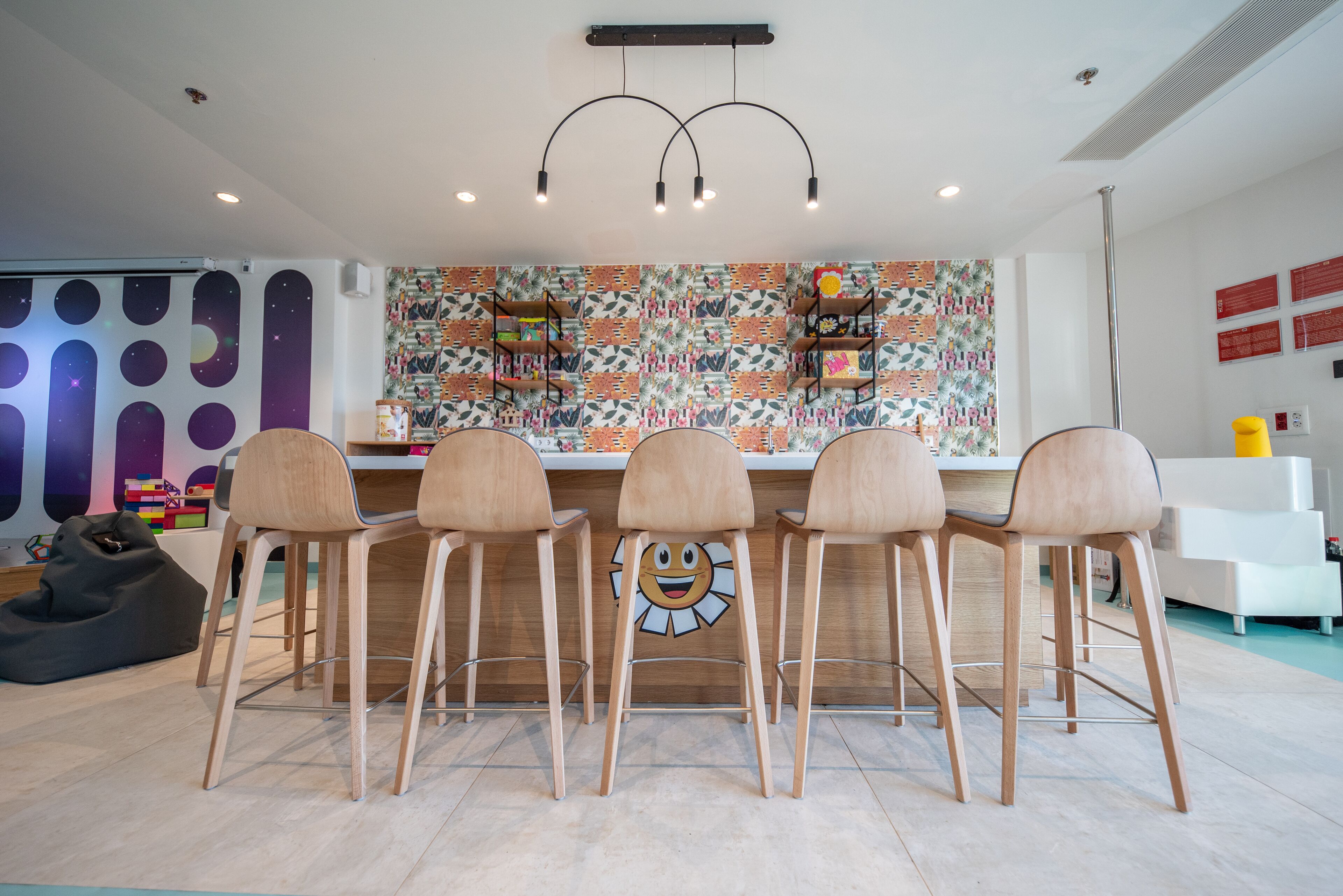 Una cocina moderna con un salpicadero colorido, taburetes de bar de madera y una decoración mural original.