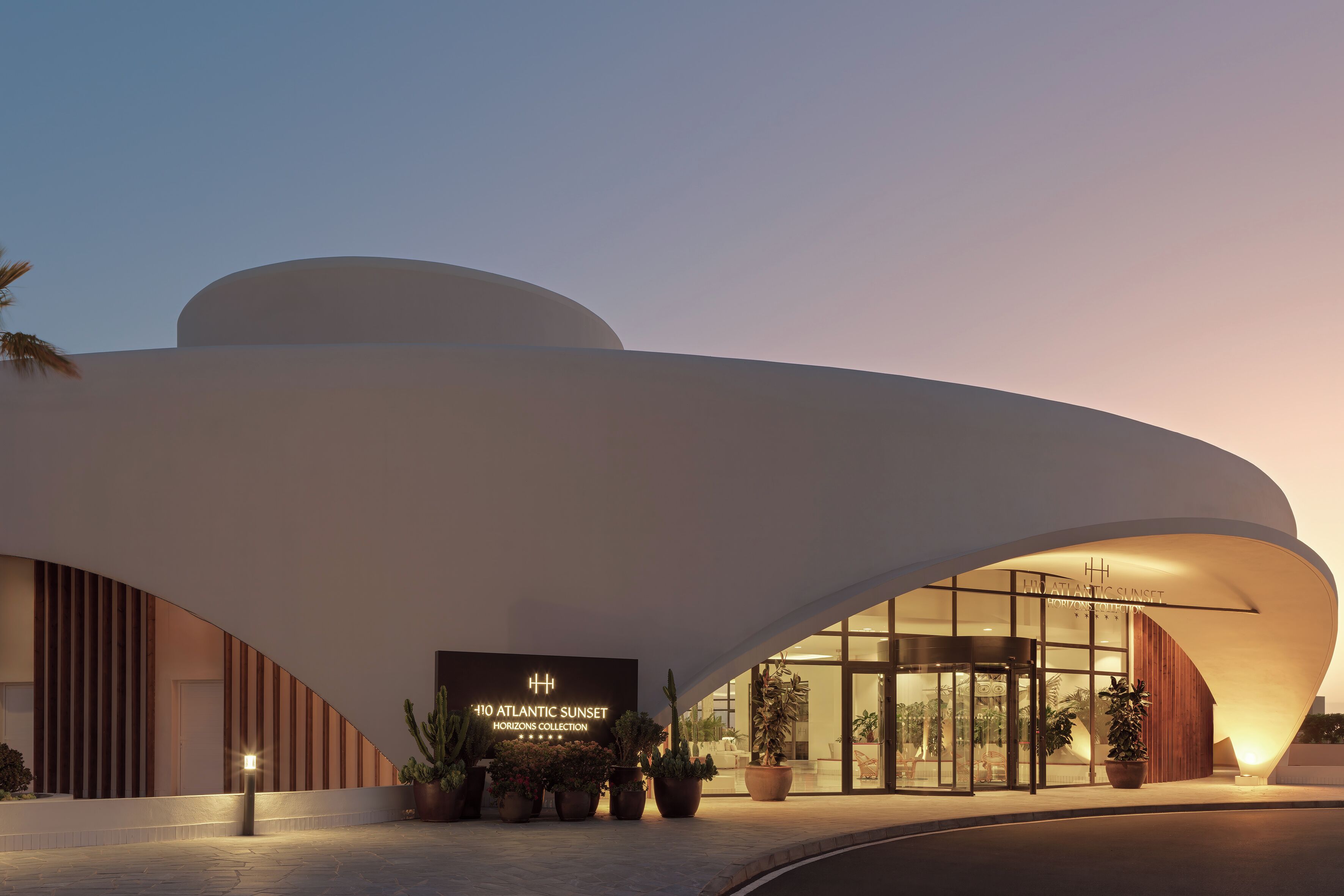 Een modern gebouw met een gebogen gevel en een bord waarop 'HORIZONS COLLECTION' staat.