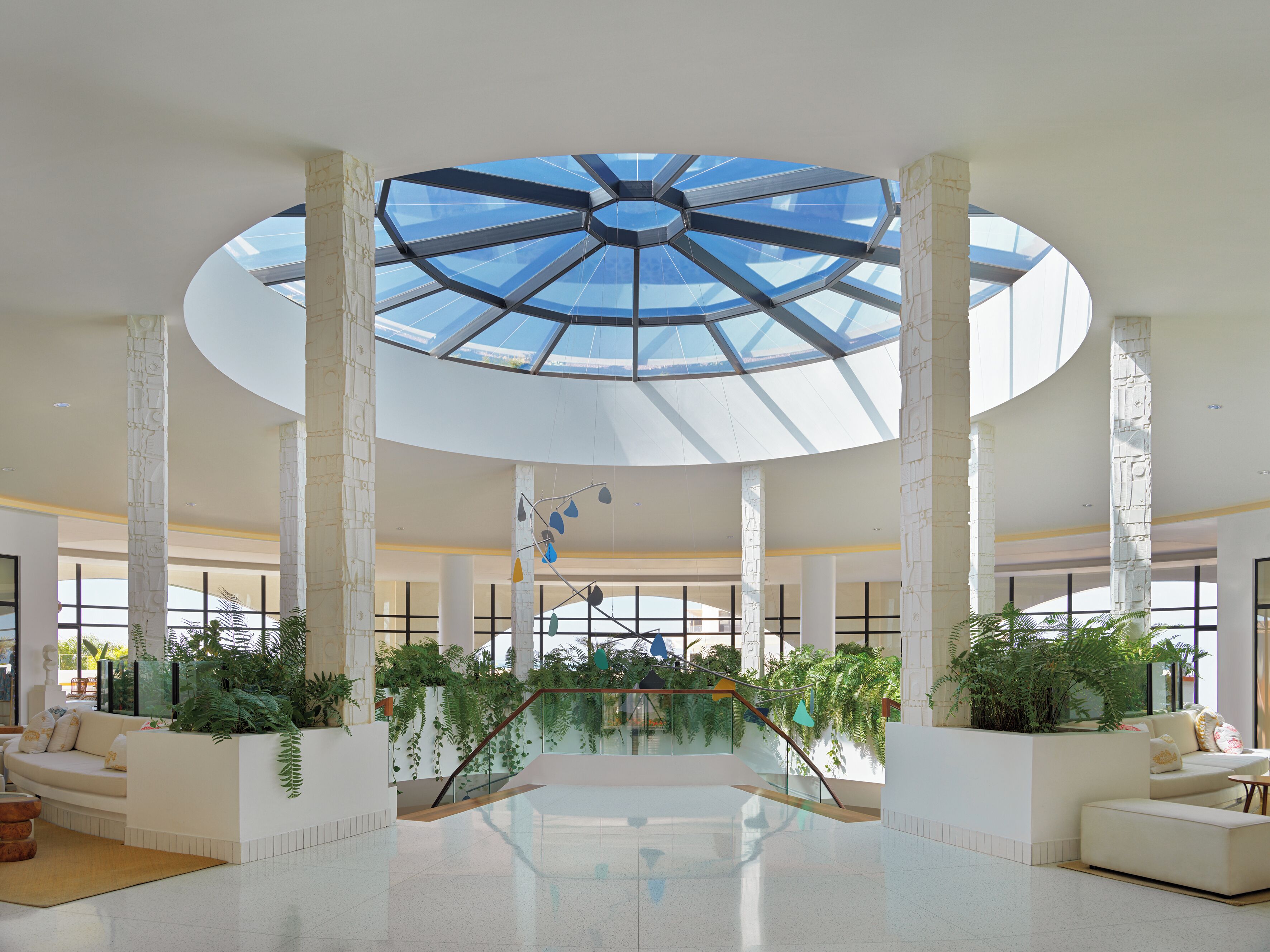 A spacious atrium with a high ceiling, large windows, and a central staircase.